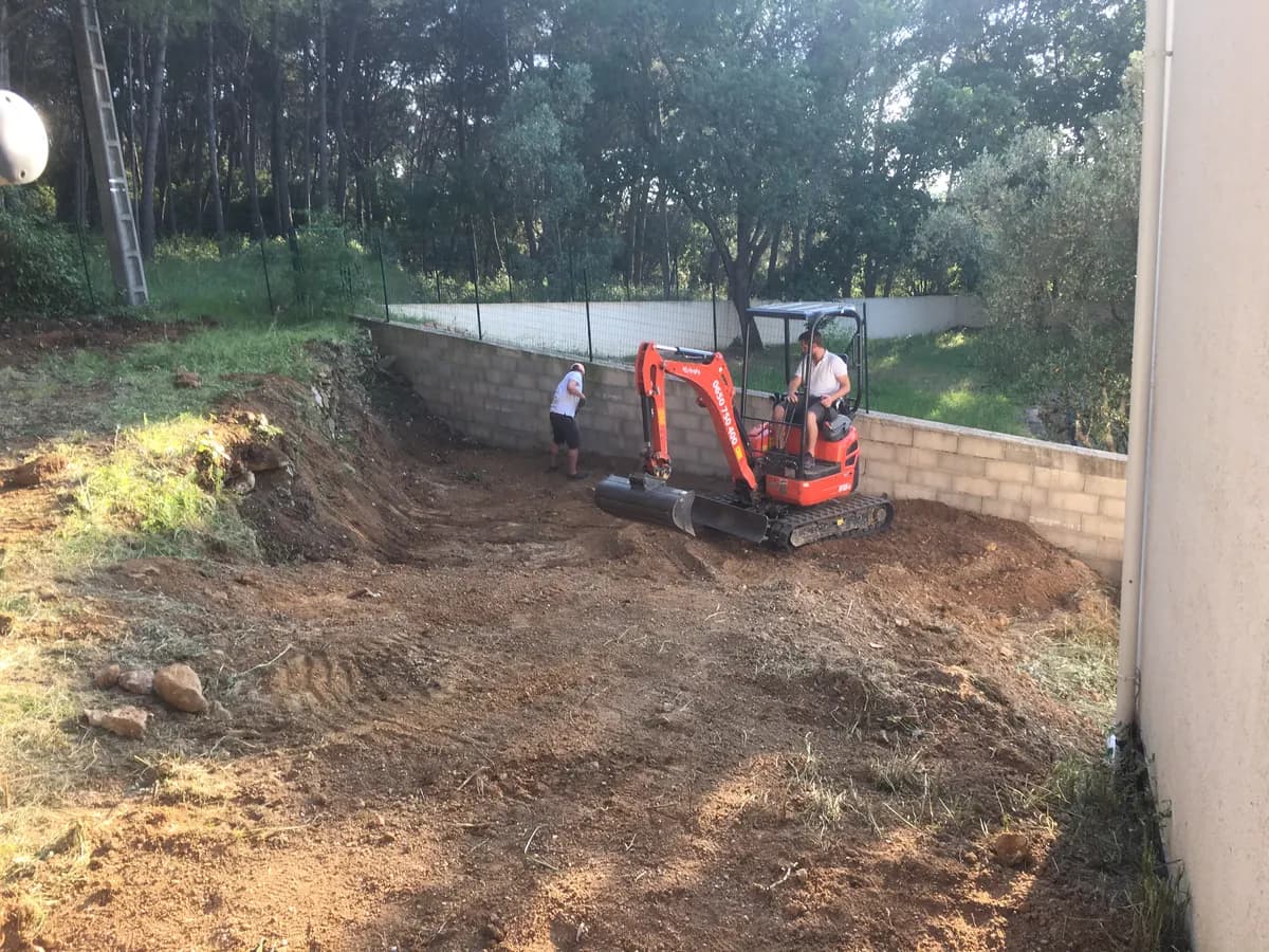 Plateforme de terre nivelée le long du mur de clôture, à la fin du terrassement