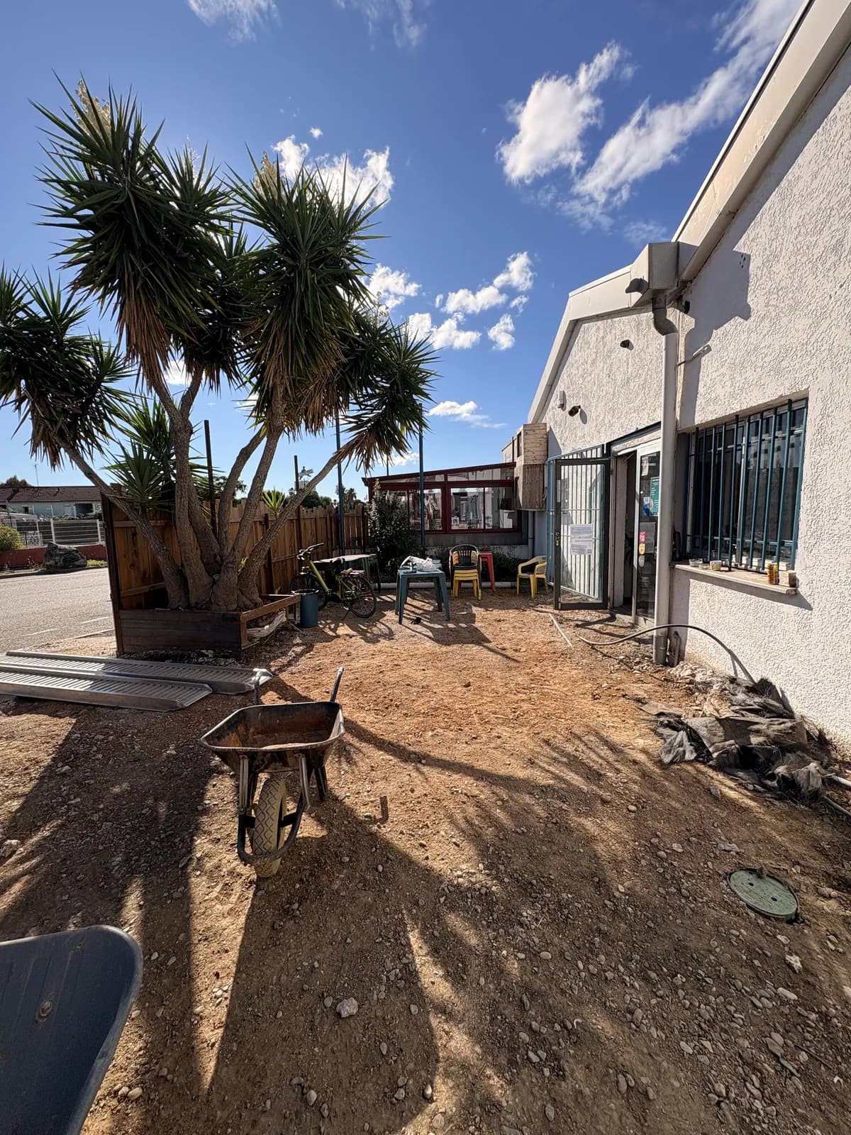 Sol décaissé et nivelé devant l'entrée du club, prêt pour la terrasse en bois