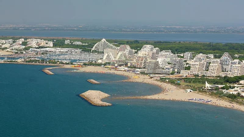 Vue aérienne de La Grande-Motte : immeubles en pyramide, port de plaisance et plage, avec les étangs en arrière-plan