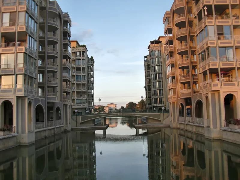 Bassin de Port Ariane à Lattes, bordé d'immeubles à arcades, avec une passerelle au fond